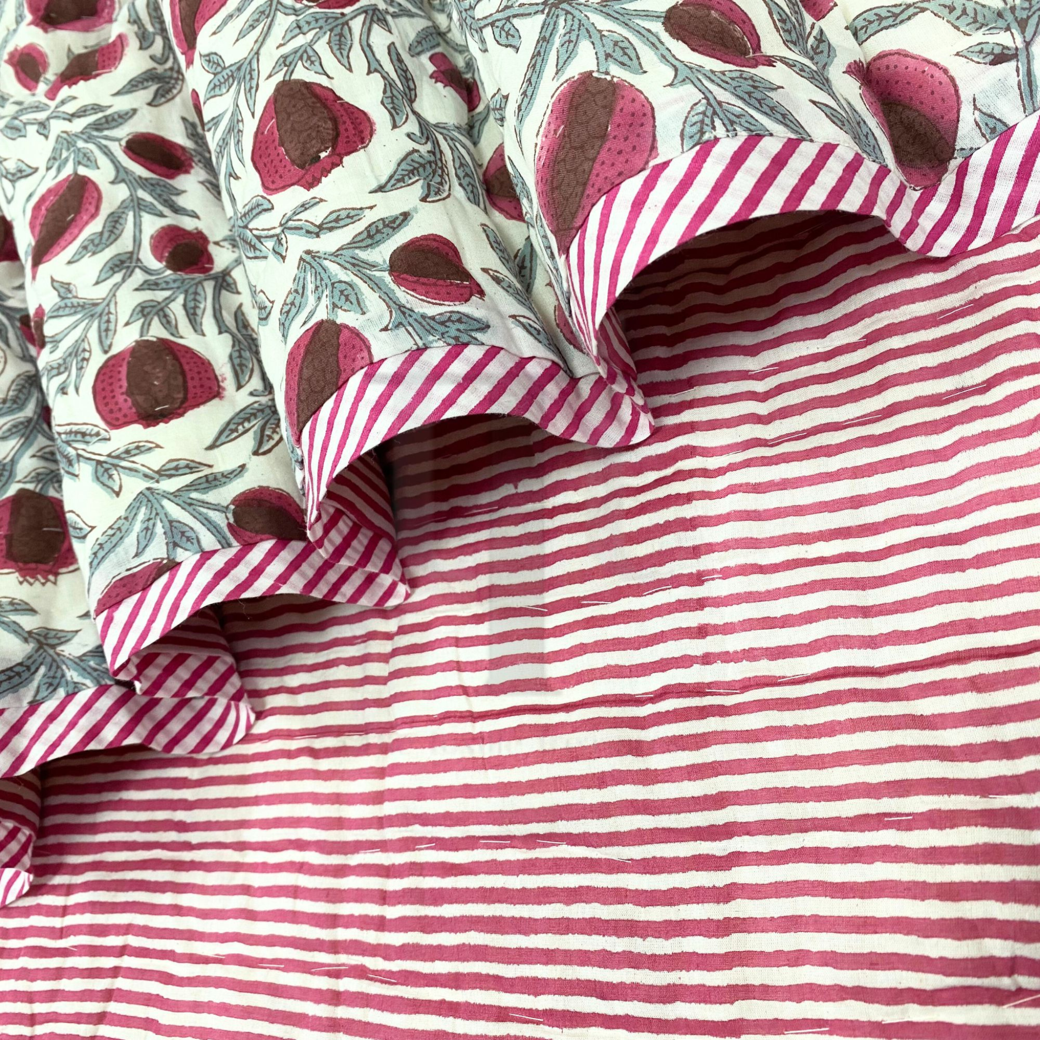Close-up of fabric with pomegranate pattern and red and white striped fabric