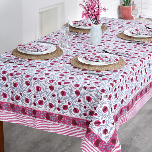 Dining table set with a floral patterned tablecloth in a bright room.
