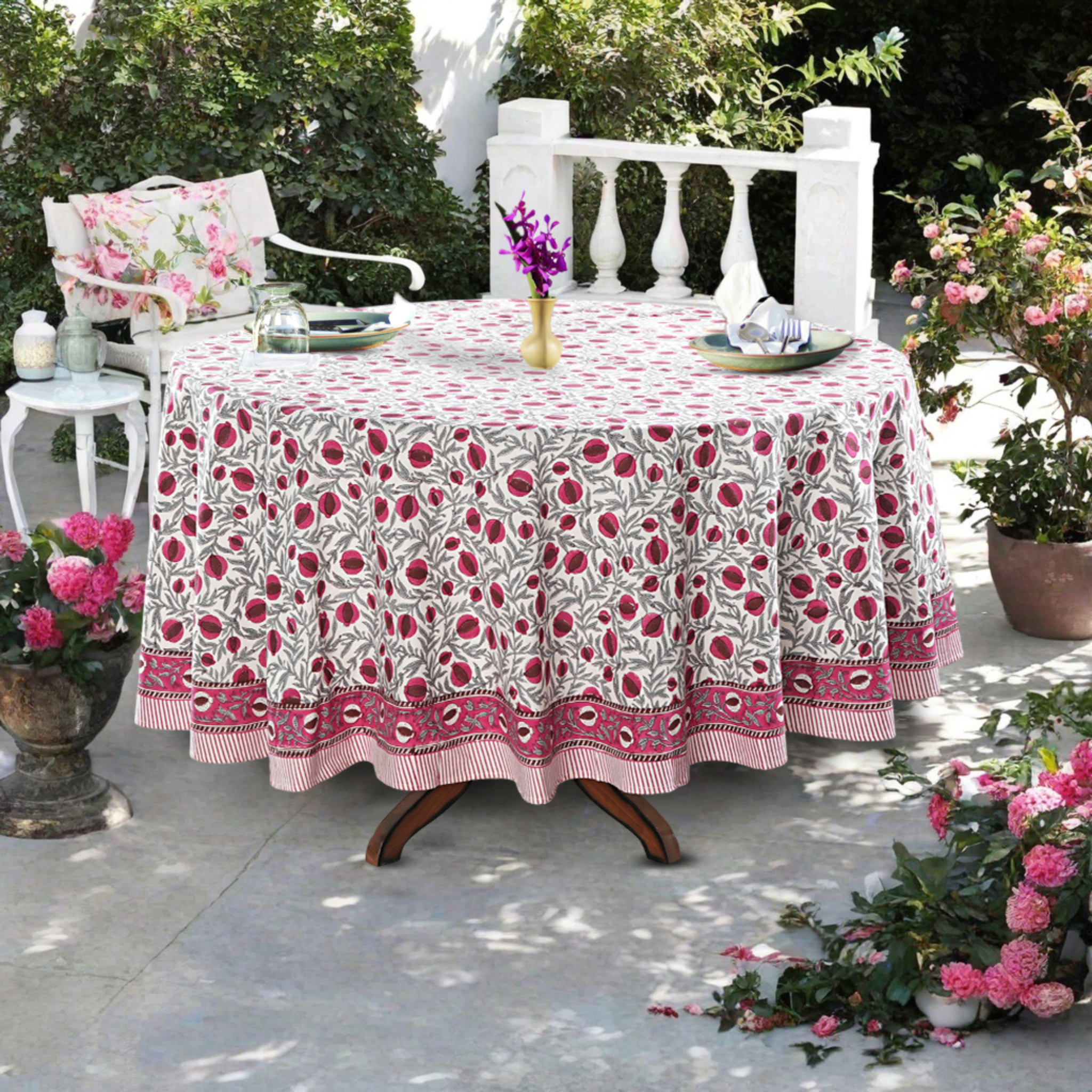 Outdoor table setting with a floral tablecloth, chairs, and decorative elements.