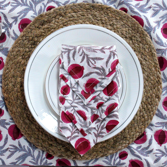 Placemat with a white plate and red floral napkin on a patterned tablecloth.