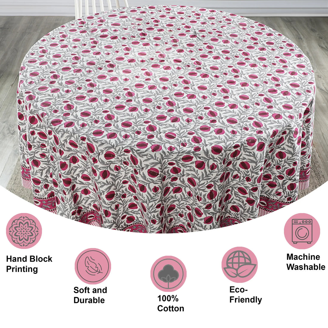Round tablecloth with pink floral pattern on a wooden floor, featuring icons and text about material and care.