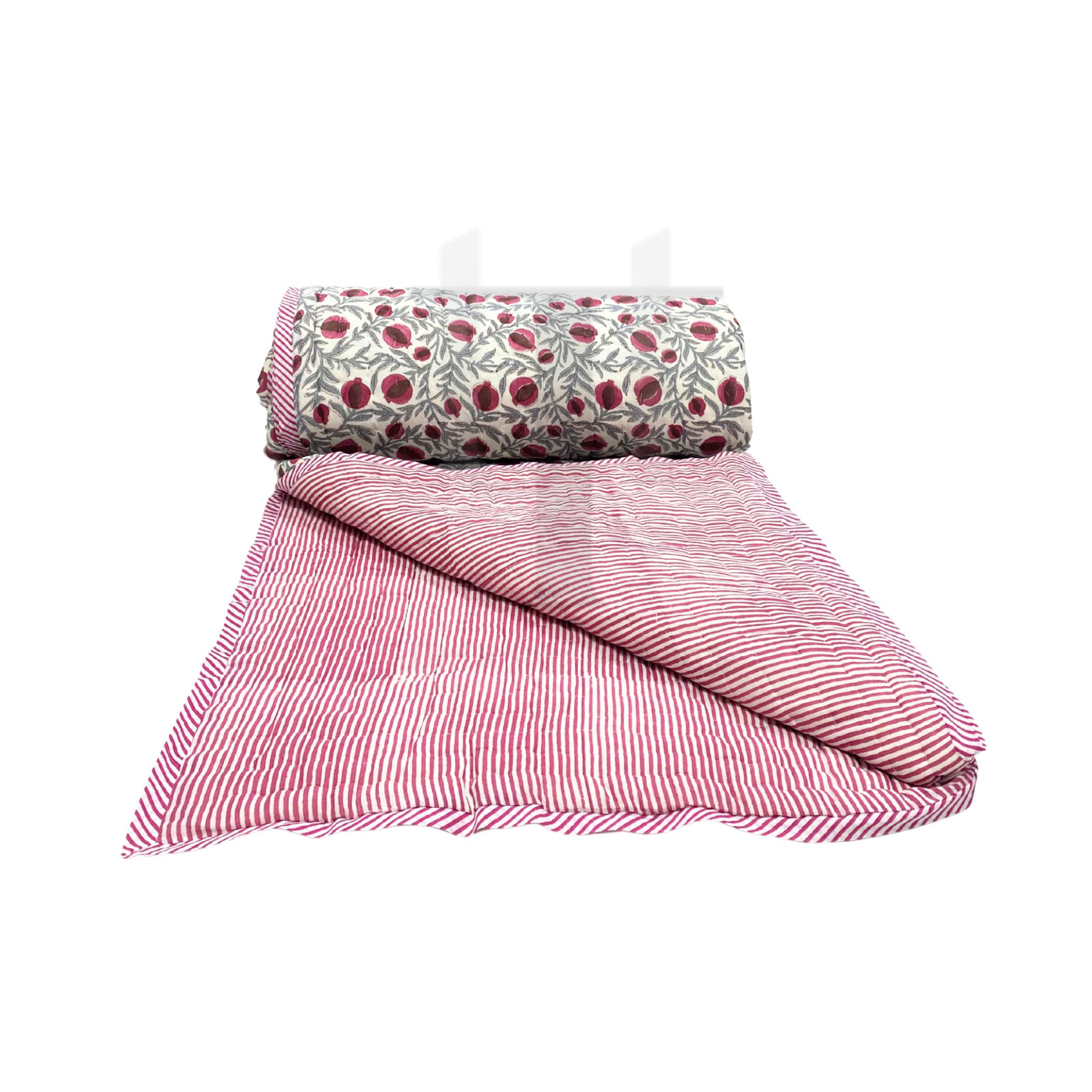 Pink striped quilt and floral-patterned pillow on a white background