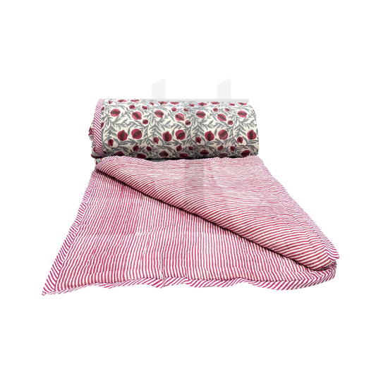 Pink striped quilt and floral-patterned pillow on a white background