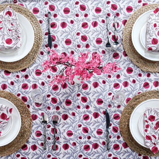Table setting with a floral tablecloth and pink cherry blossom centerpieces.