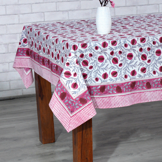 Tablecloth with floral pattern on a wooden table against a white brick wall.