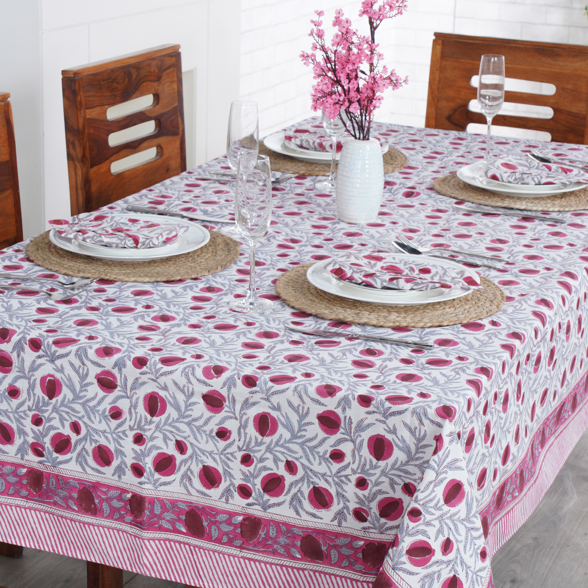 Dining table set with a floral tablecloth, plates, glasses, and cutlery.