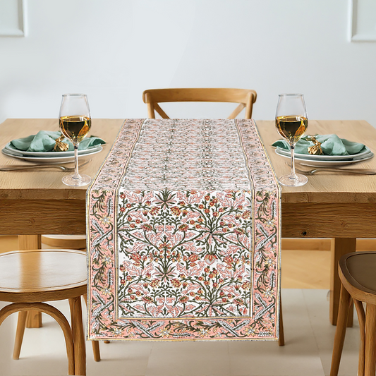 Dining table set with a floral patterned table runner, glasses, and plates.