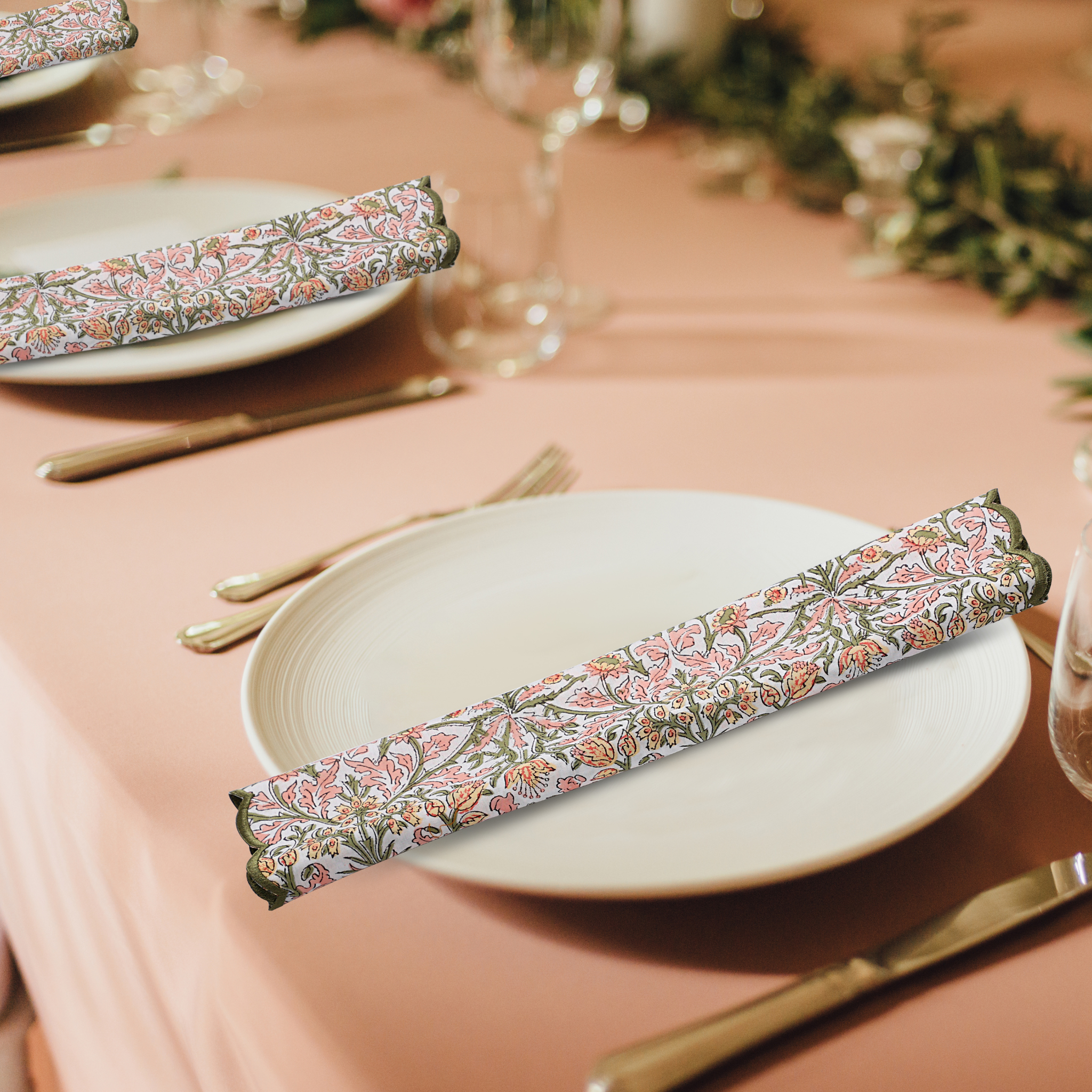 Decorative floral-patterned napkins on a table setting with pink tablecloth and greenery.