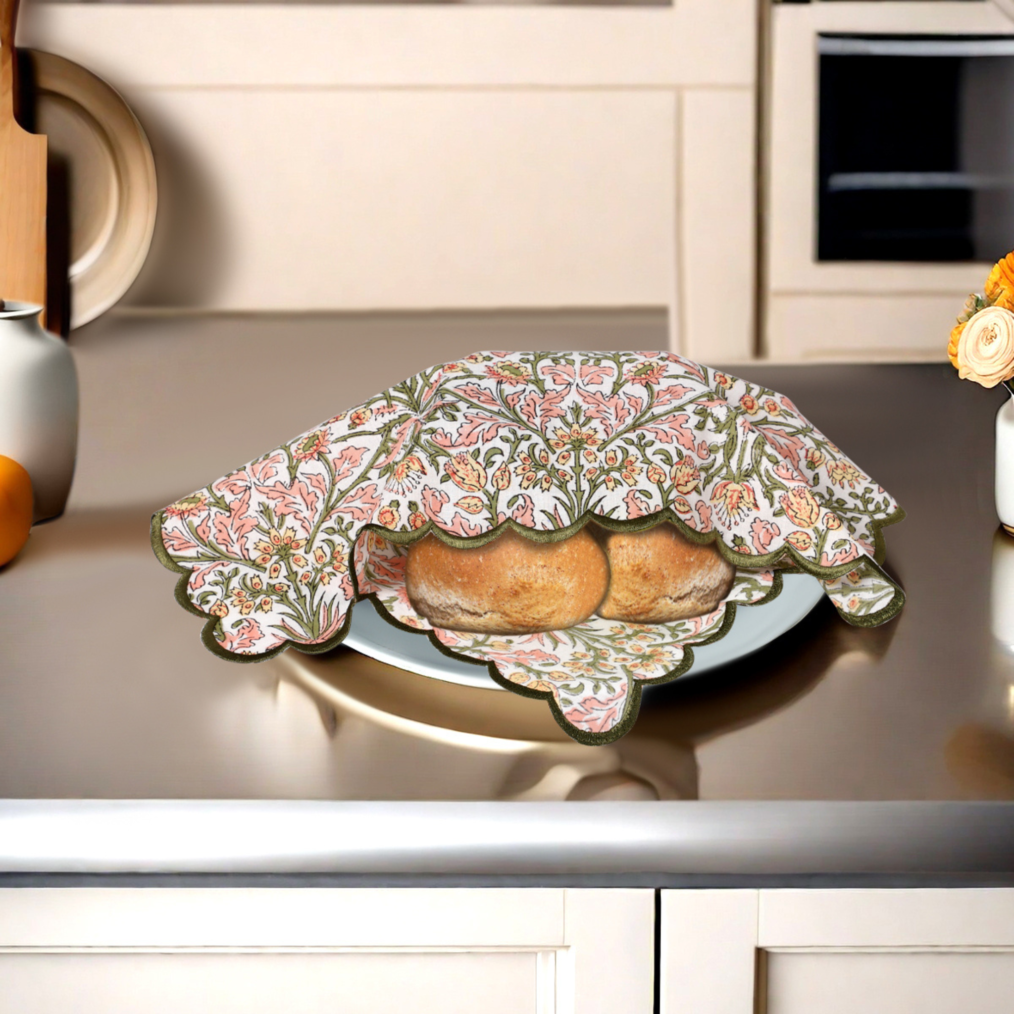 Decorative floral cover on a plate with bread on a kitchen counter.