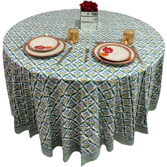 Round table with a patterned tablecloth, plates, and glasses on a white background