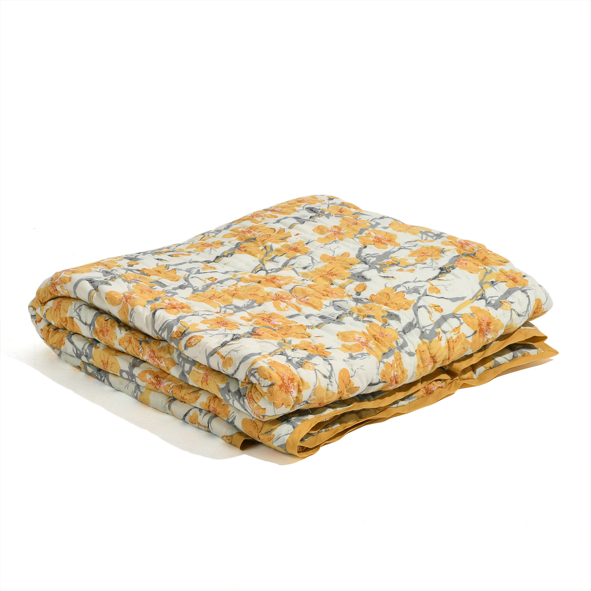 Folded floral quilt with yellow and gray pattern on a white background