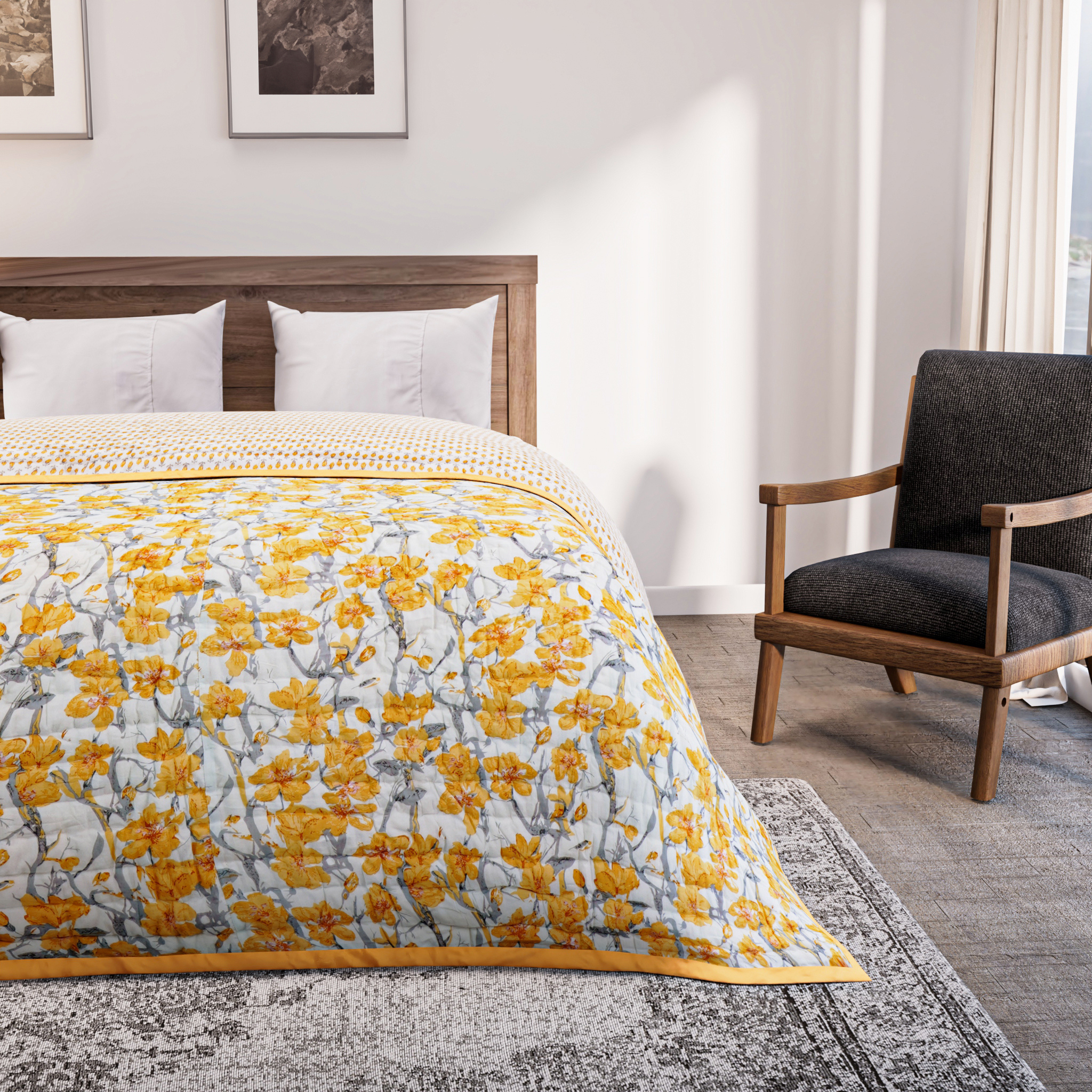 Bedroom with a bed covered in a yellow floral comforter, gray armchair, and framed artwork on the wall.