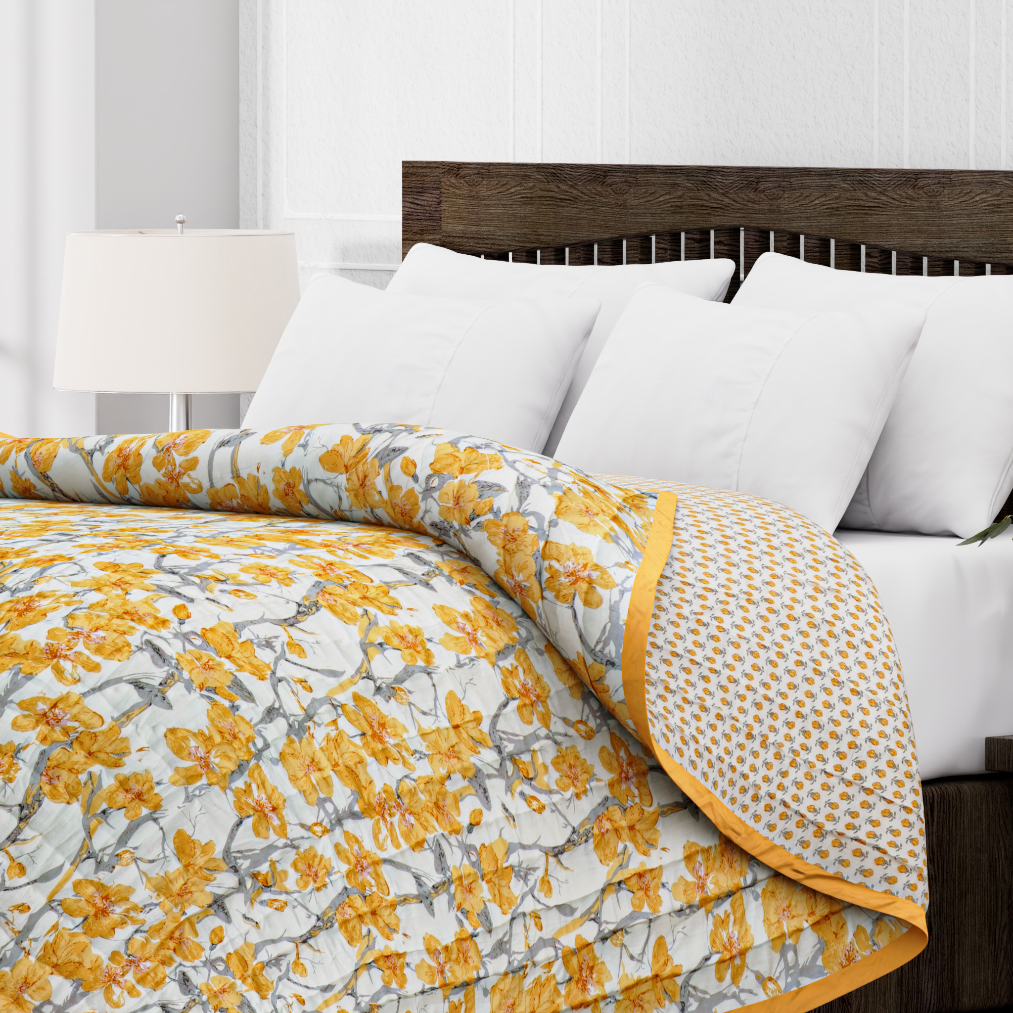 Floral quilt with yellow and gray pattern on a bed with white pillows and wooden headboard.