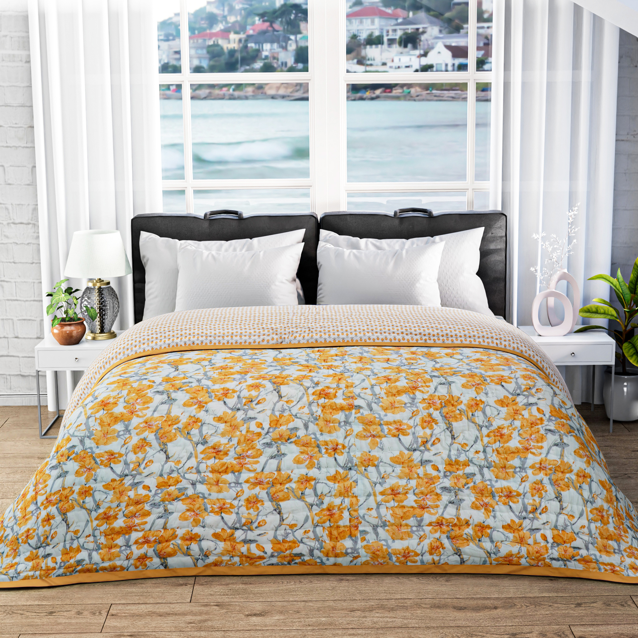 Bed with yellow floral comforter in a room with large windows showing a waterfront view.