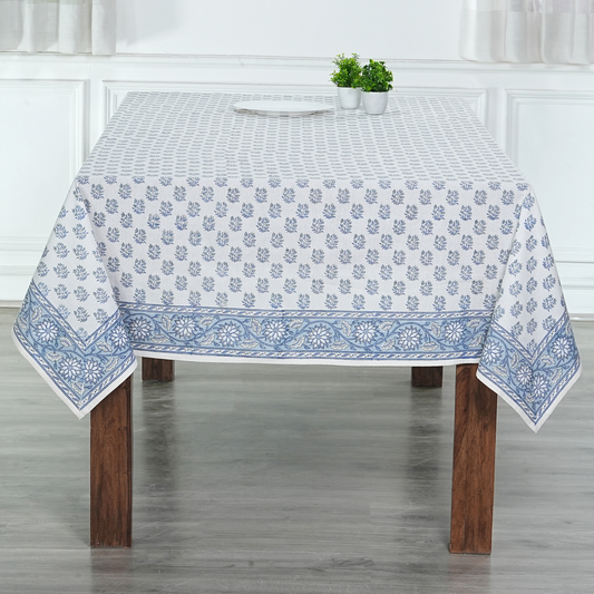 Tablecloth with blue floral pattern on a wooden table in a room with white walls.