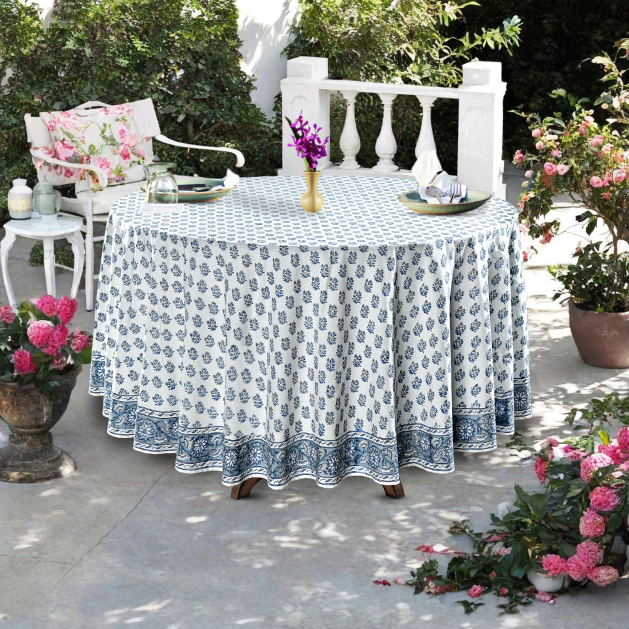 Outdoor table setting with a floral-patterned tablecloth, chairs, and decorative elements.