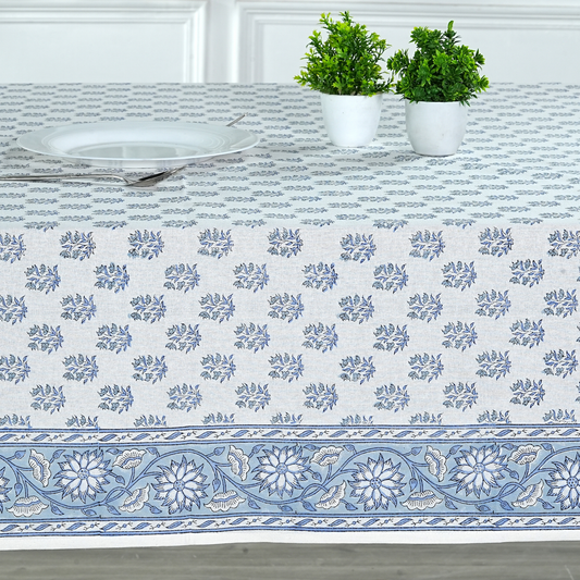 Tablecloth with blue floral pattern on a table with plants and plates.