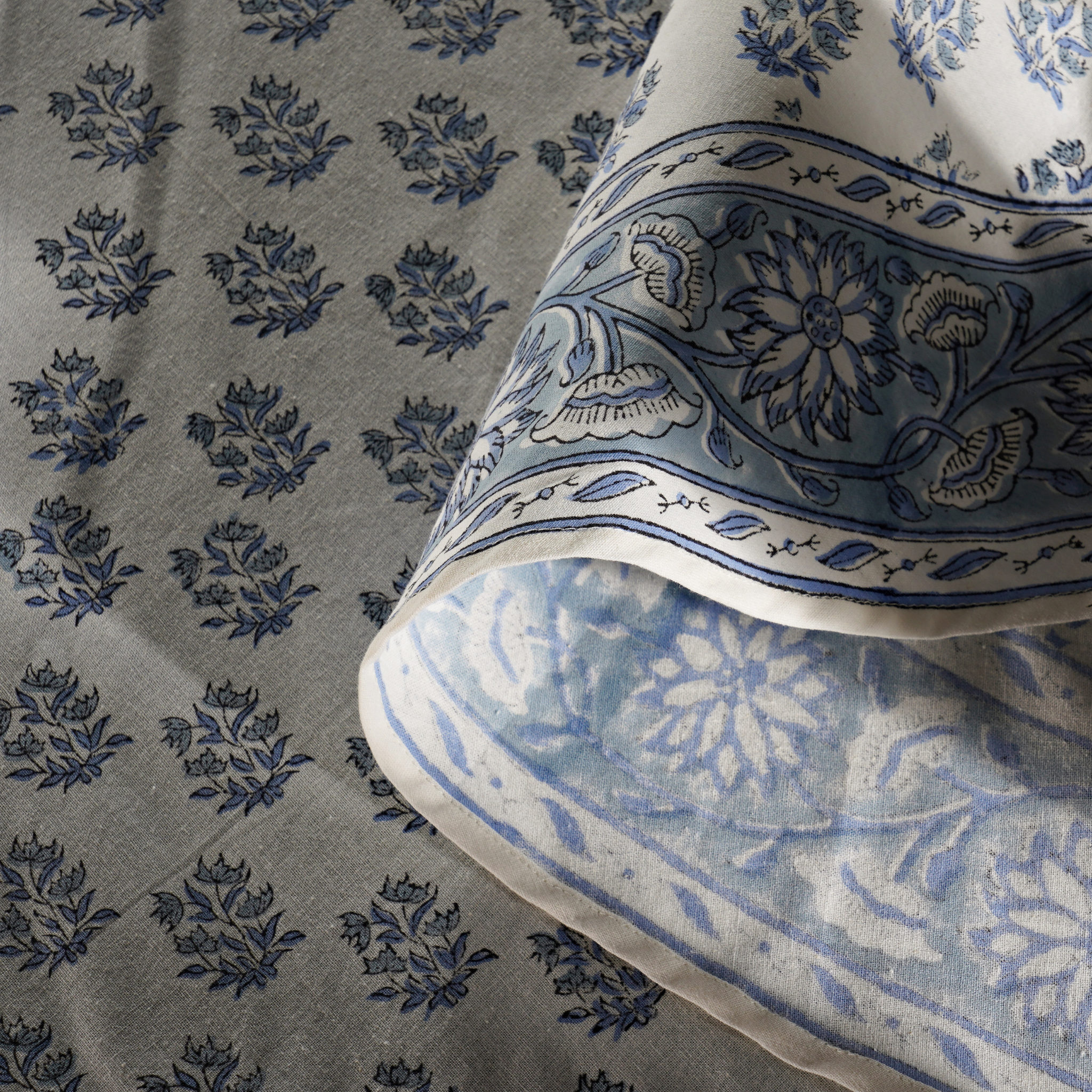 Close-up of blue floral patterned fabric with a pillow featuring similar design.