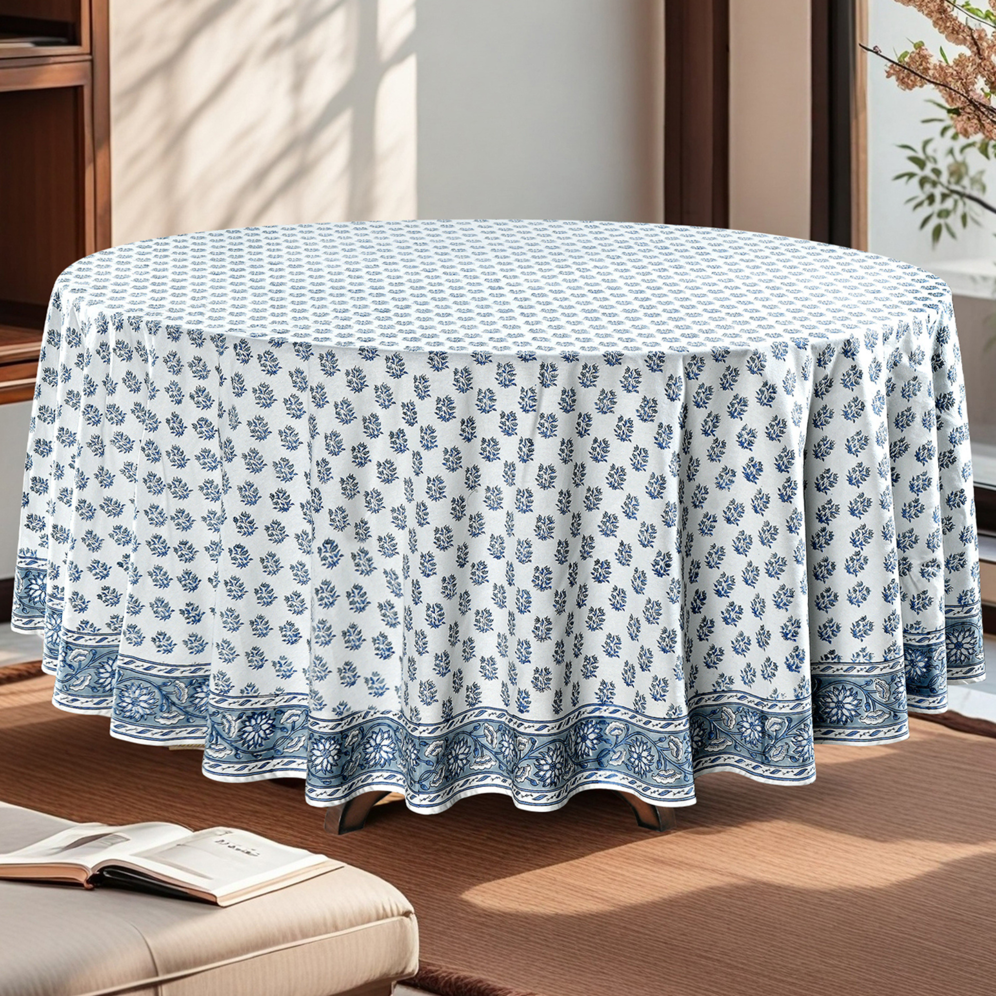 Round table covered with a blue and white floral patterned tablecloth in a room.