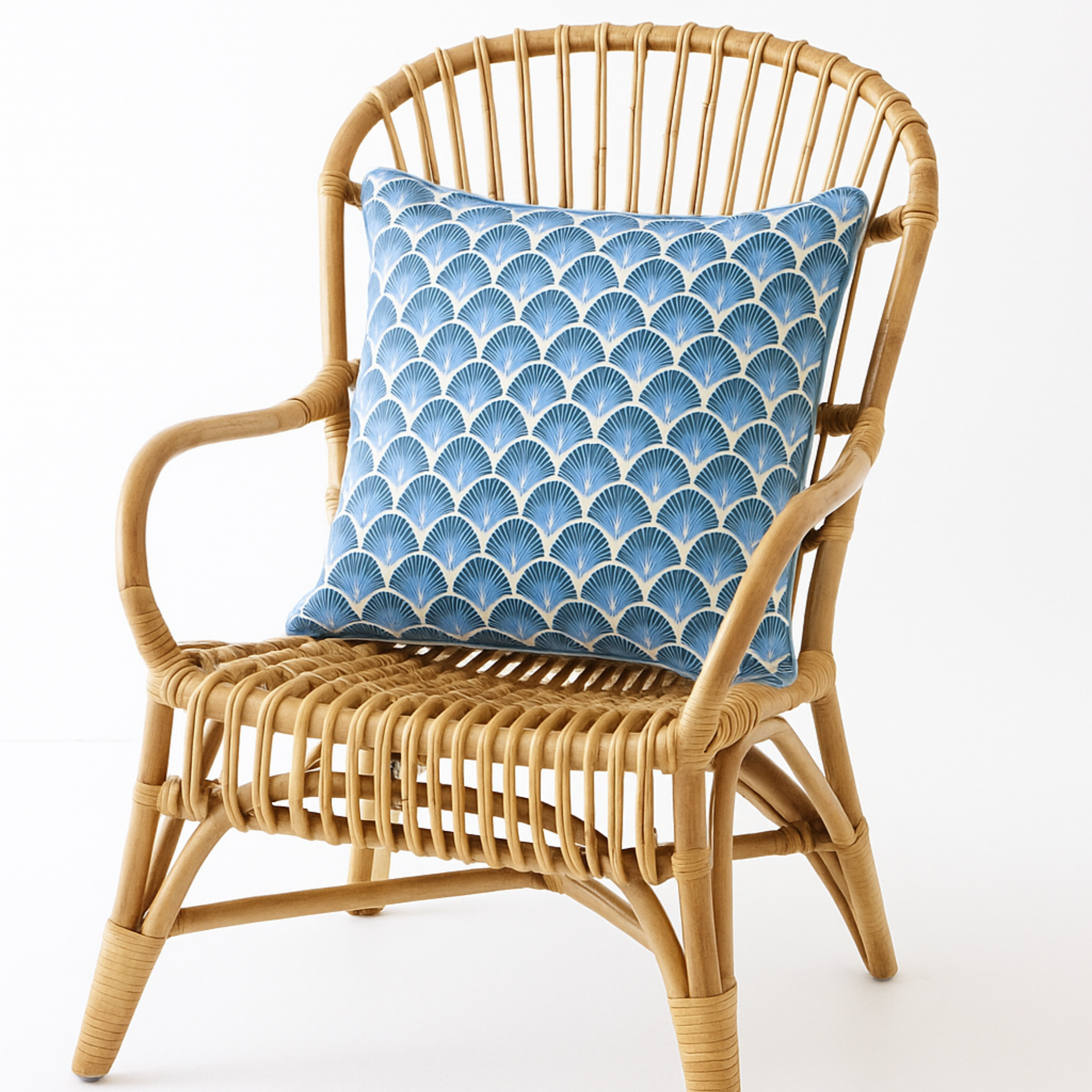 Wicker chair with a blue patterned pillow on a white background