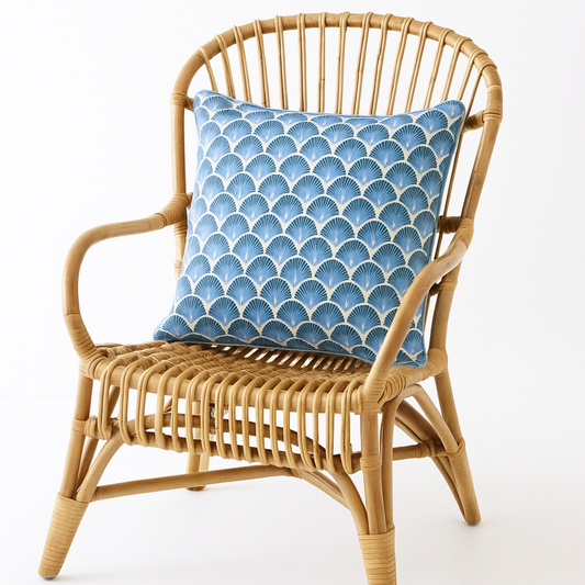 Wicker chair with a blue patterned pillow on a white background