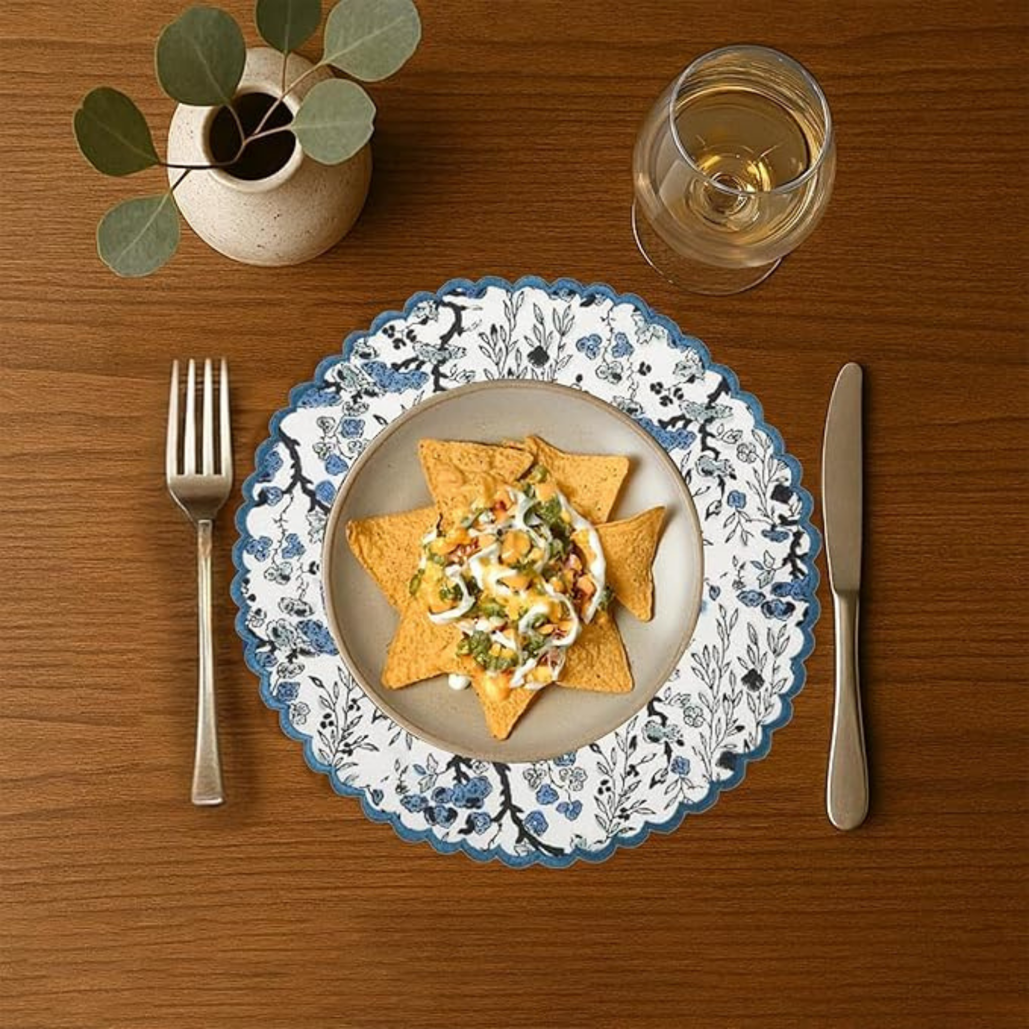 Dinner setting with a plate of food, fork, knife, and glass on a wooden table.