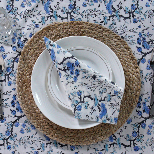 Plated dish with a folded floral napkin on a decorative tablecloth.