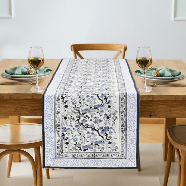 Dining table set with a decorative table runner featuring floral patterns.