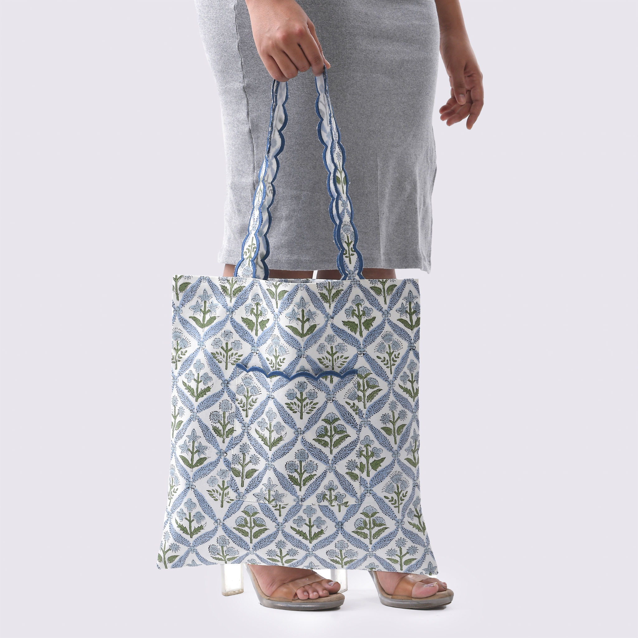 Person holding a patterned tote bag against a plain background