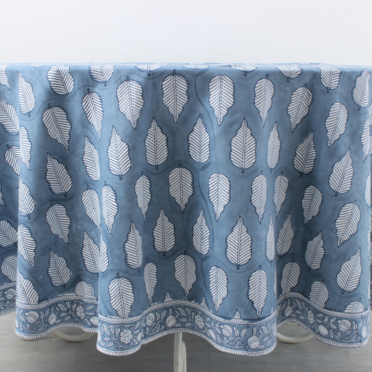 Blue tablecloth with white leaf pattern on a stand against a white background
