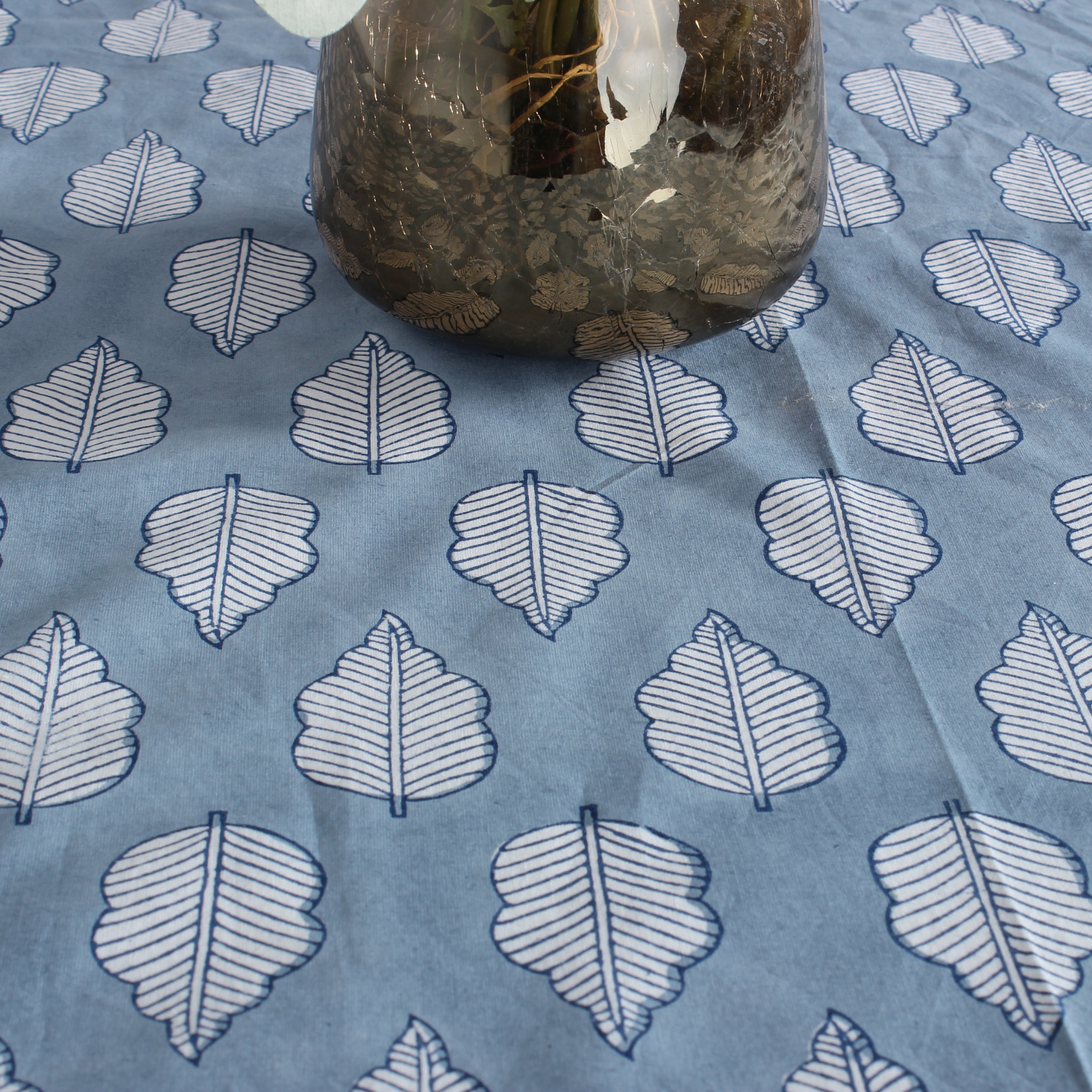 Blue fabric with white leaf pattern and a glass jar on top