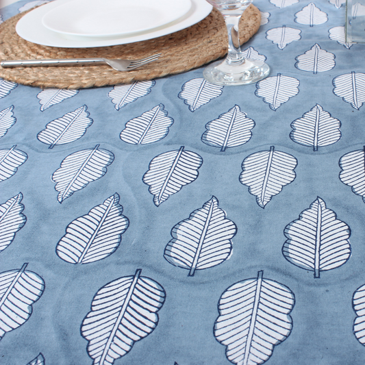 Table setting with a blue tablecloth featuring white leaf patterns.