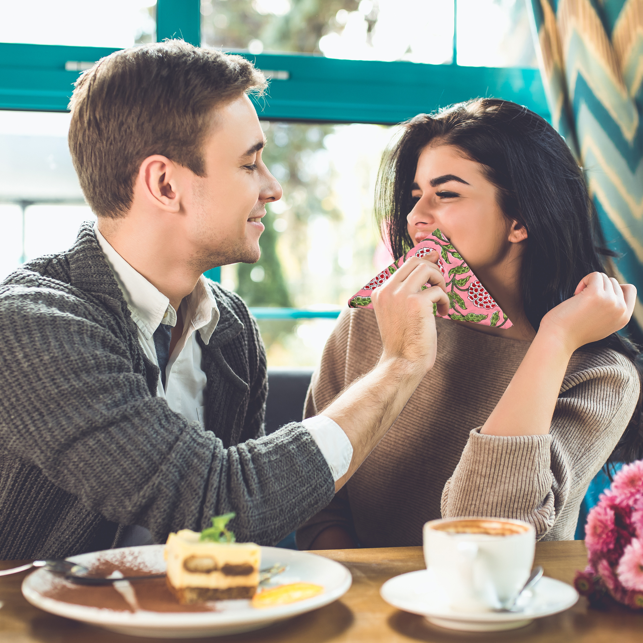 Man and woman sharing a moment at a cafe with a cup of coffee and cake.