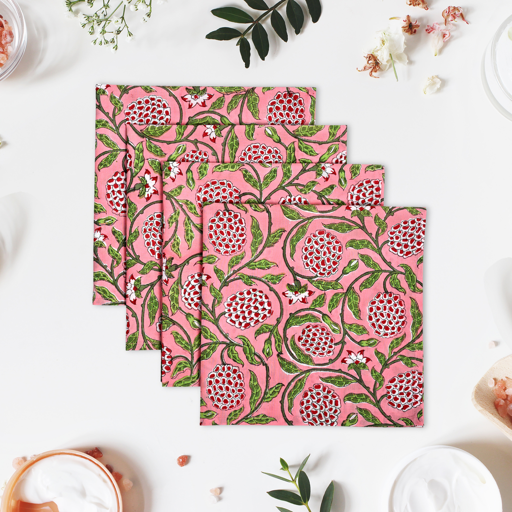 Set of four pink floral patterned napkins on a white surface with decorative elements.