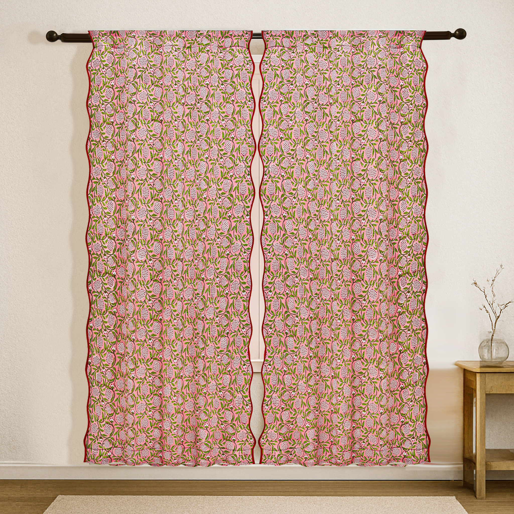Decorative pink and green floral curtain hanging on a rod against a white wall.