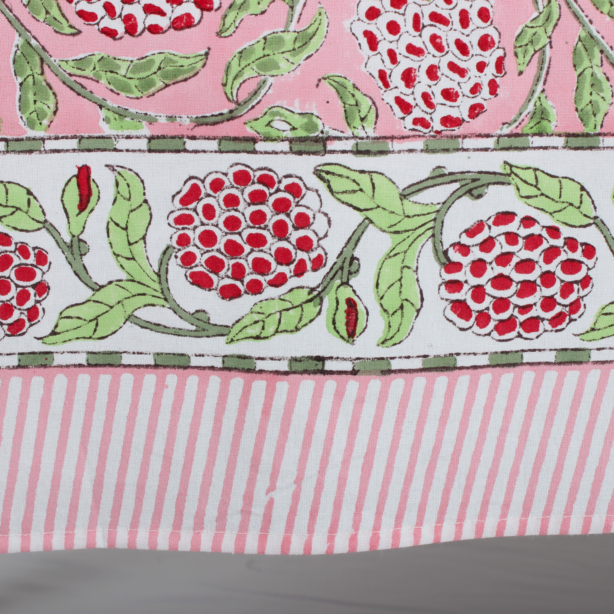 pink decorative tablecloth with striped border on wooden