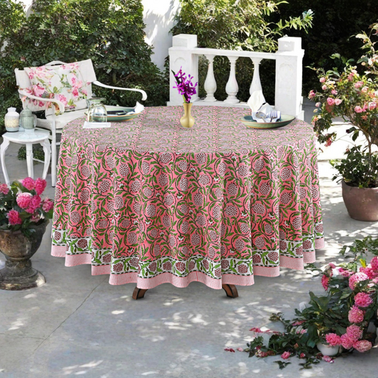 Round table with a pink and green patterned tablecloth outdoors on a patio.