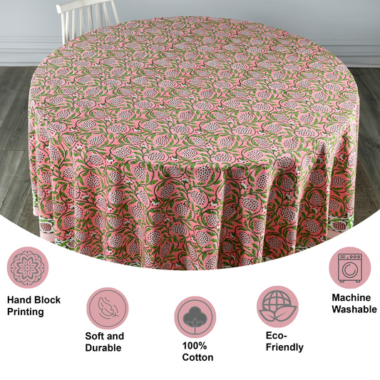 Round tablecloth with pink and green floral pattern on a wooden floor.