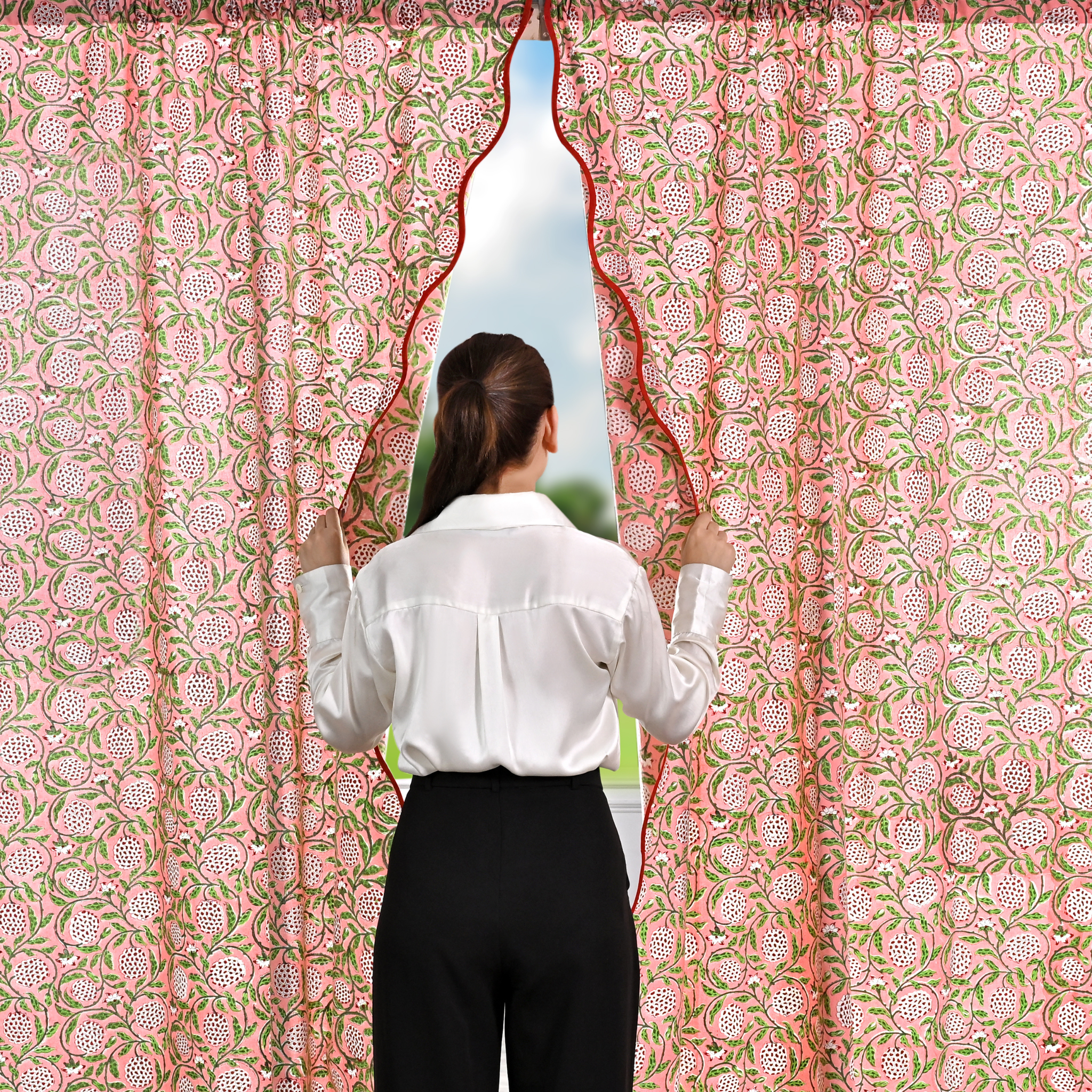 Person opening a floral patterned curtain to reveal a view of trees.