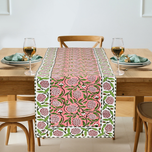 Table setting with a pink and green patterned table runner on a wooden table.