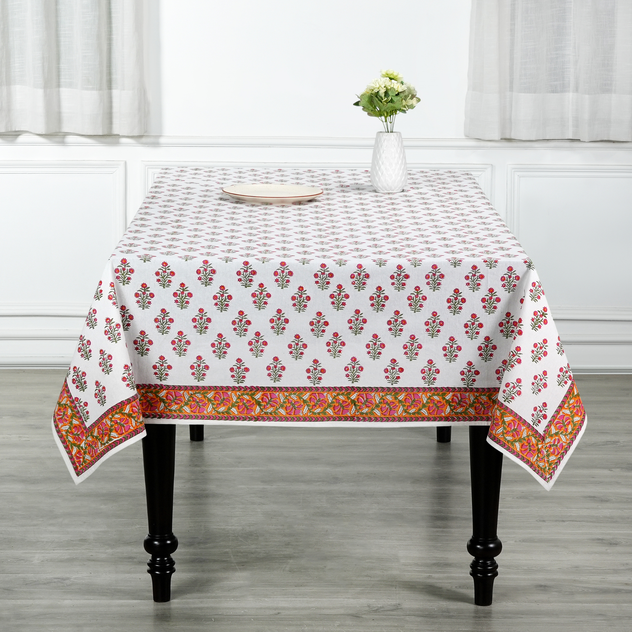 Tablecloth with floral pattern on a table in a room with white curtains.