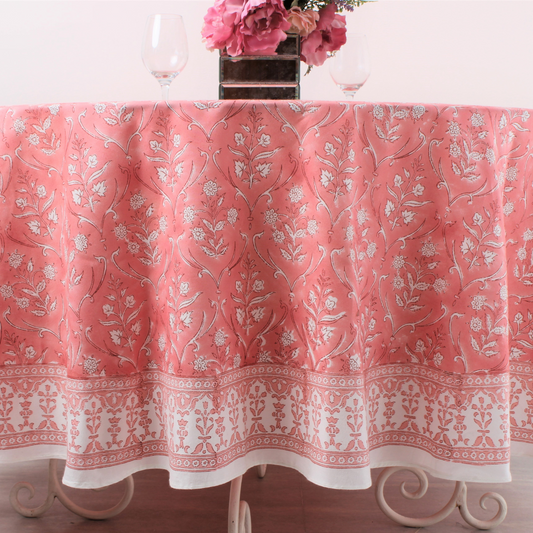 Pink floral patterned tablecloth on a table with a vase of flowers.