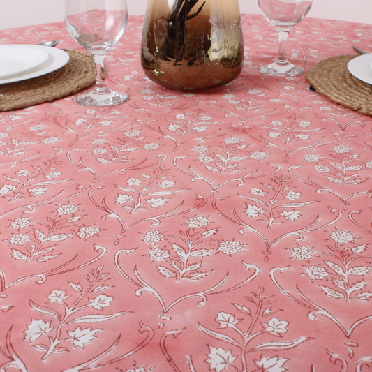 Pink tablecloth with white floral pattern on a set dining table.