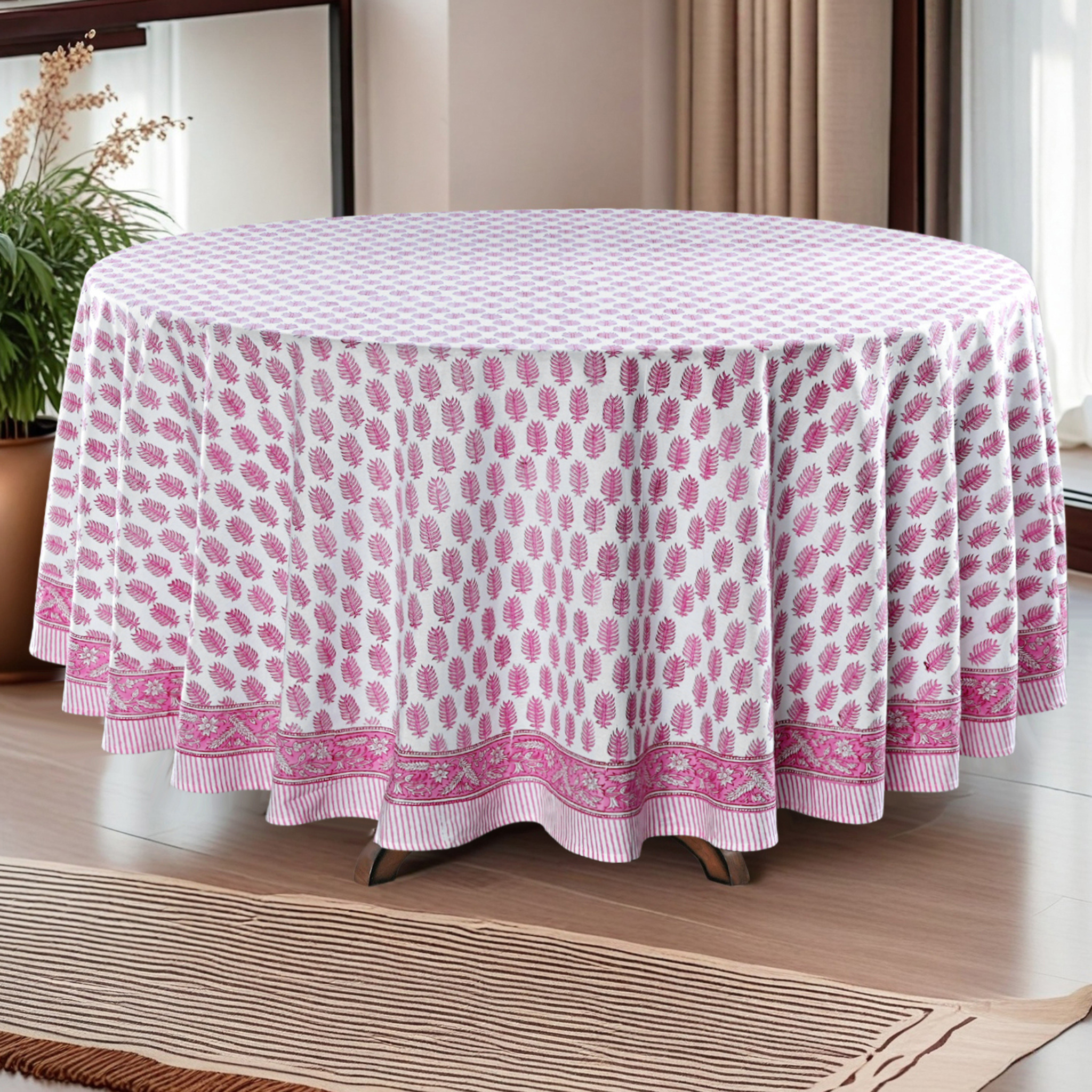 Round table covered with a pink and white patterned tablecloth in a room setting.