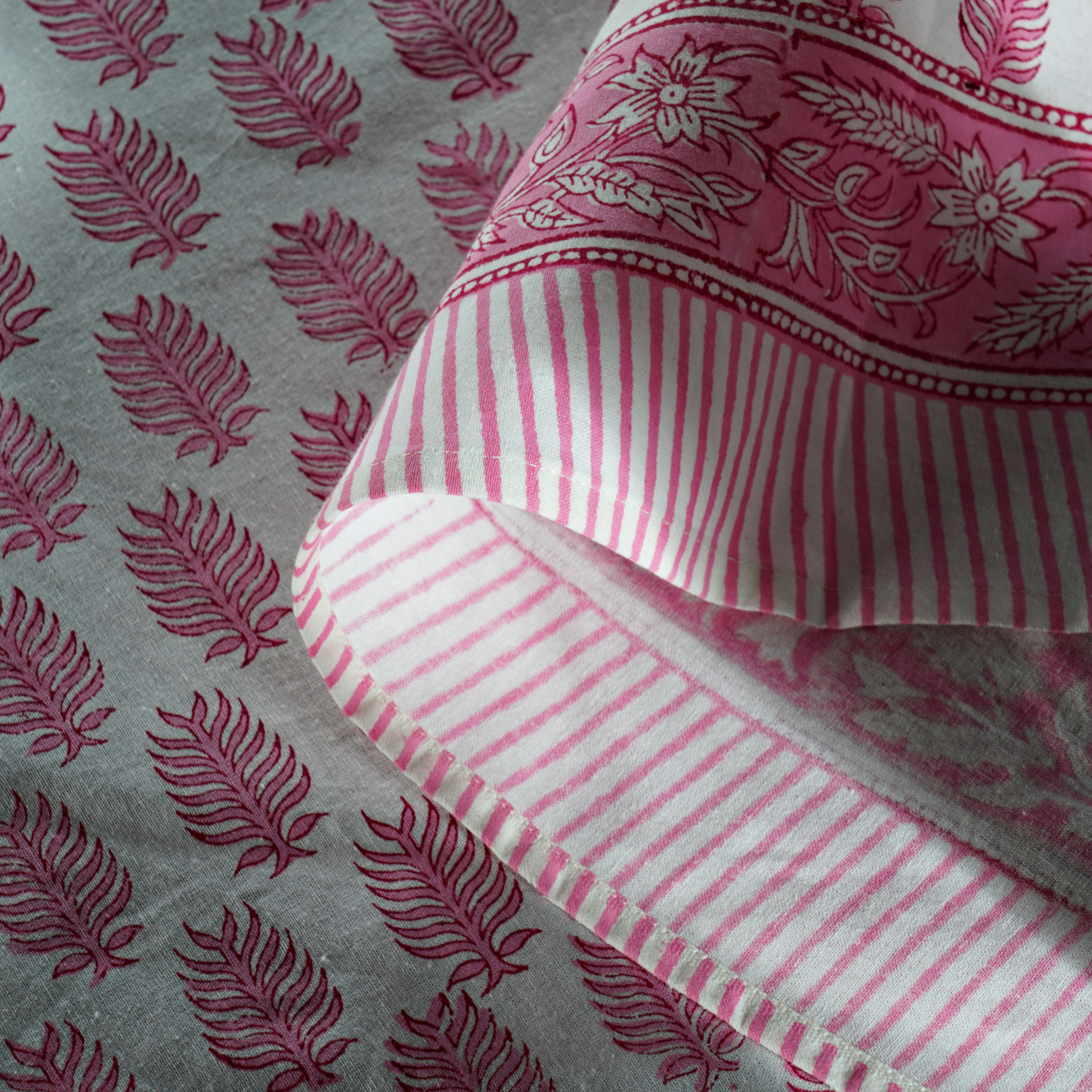 Close-up of pink and white striped fabric with floral patterns on a gray background