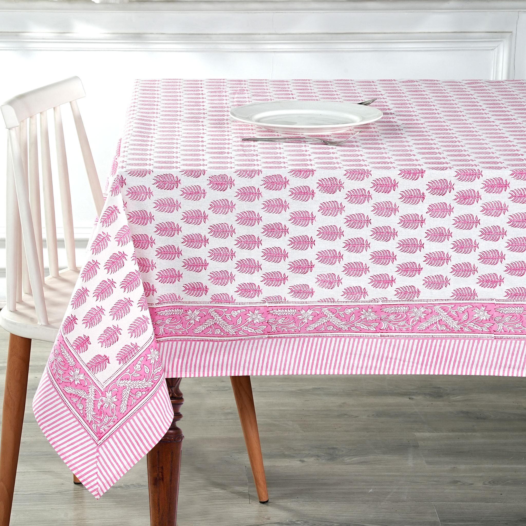 Tablecloth with pink leaf pattern on a wooden table and chair.