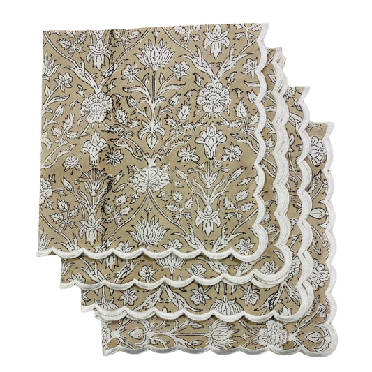 Two beige napkins with white floral patterns and scalloped edges on a white background