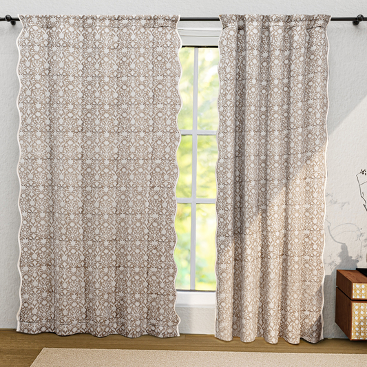 Floral patterned curtains hanging in front of a window with a light gray wall and wooden floor.