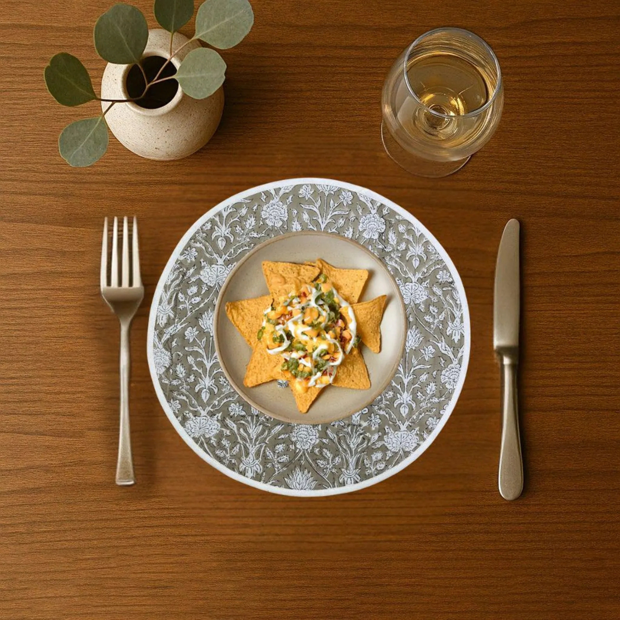 Dinner setting with a plate of food, fork, knife, and glass on a wooden table.