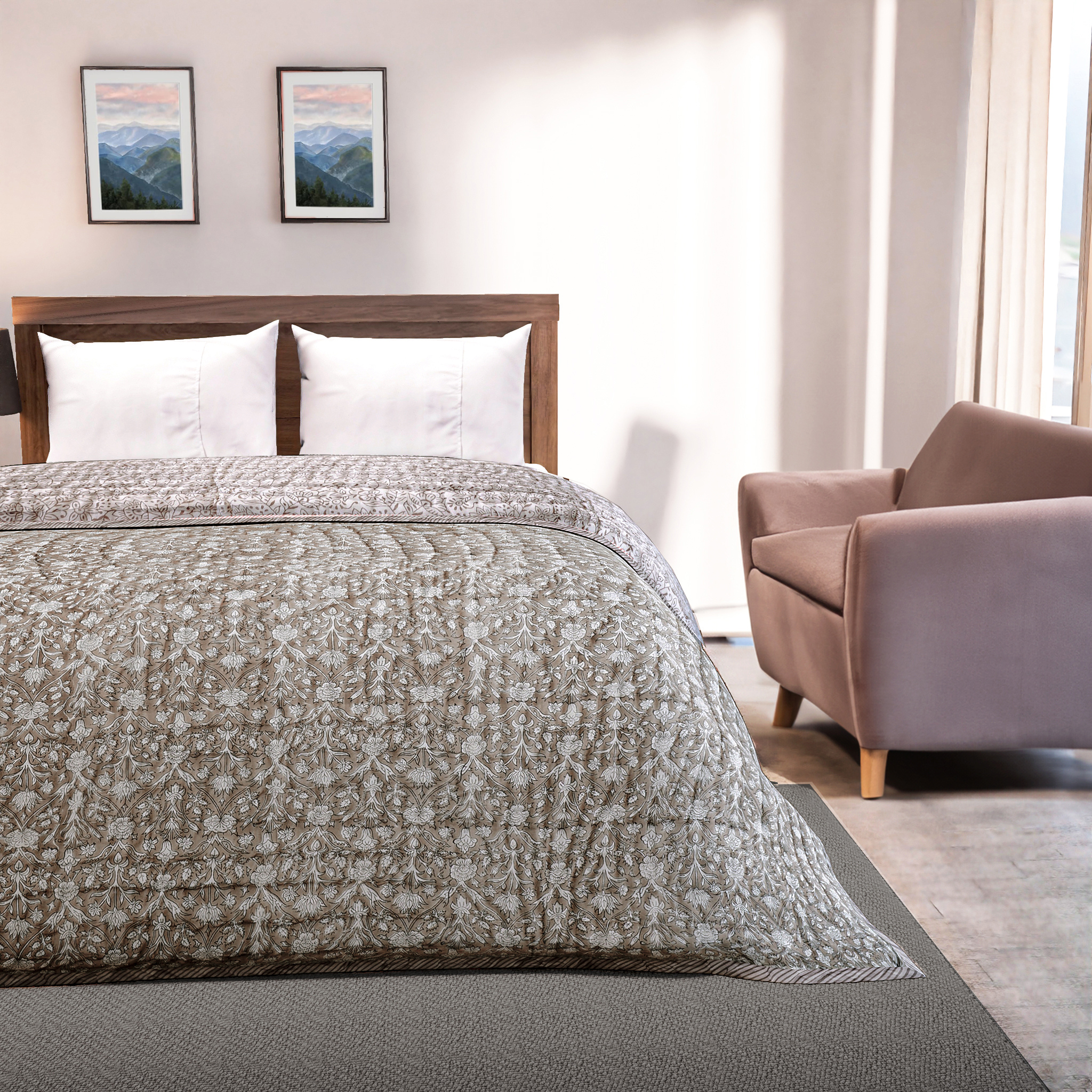 Bedroom with a bed covered in a patterned comforter, a chair, and framed pictures on the wall.